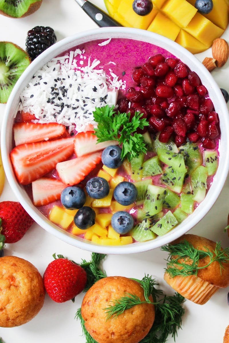 Vibrant smoothie bowl topped with assorted fresh fruits and muffins, perfect for a healthy snack.