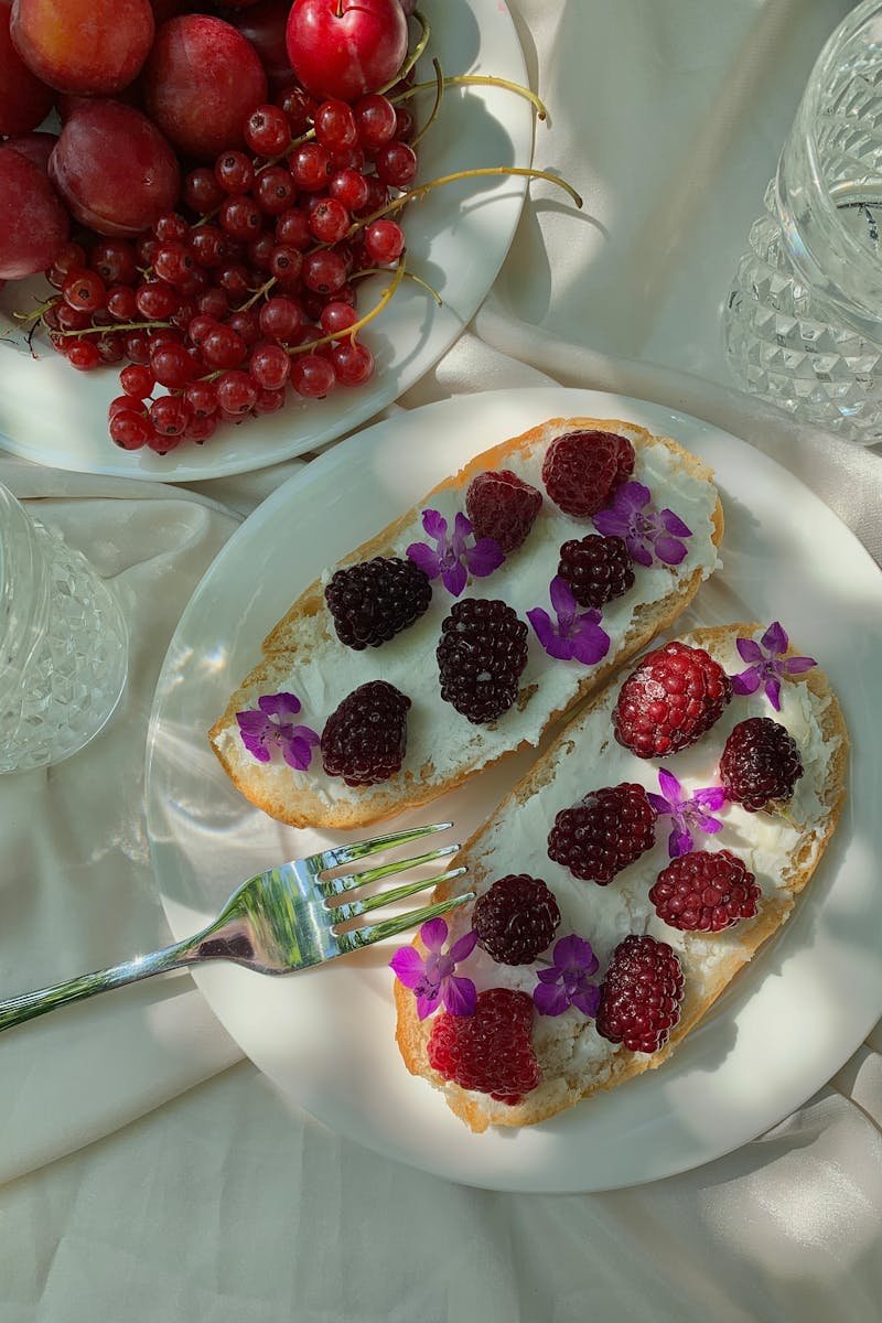 Delicious creamy breakfast topped with berries and edible flowers on a white plate.